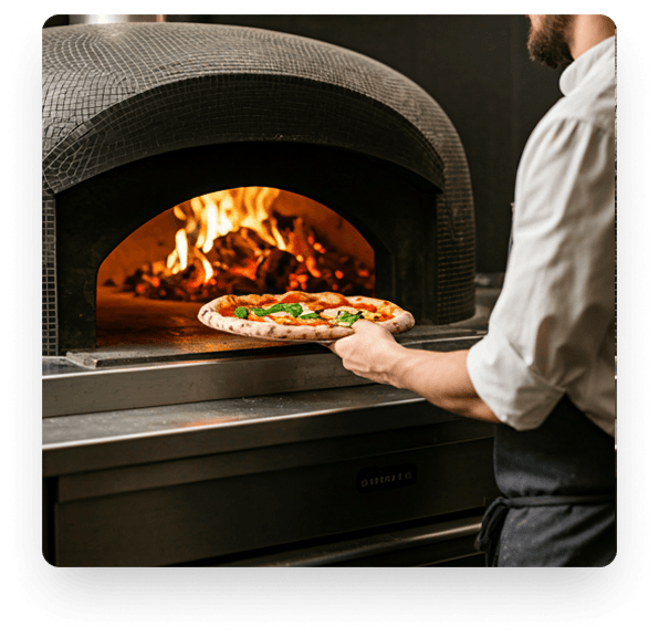 Pizzaiolo placing pizza in charcoal oven